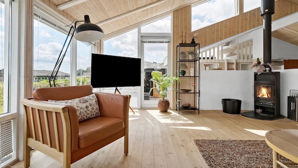 Un salon moderne avec un canapé en cuir, un téléviseur à écran plat, une cheminée et une grande fenêtre donnant sur l’extérieur.