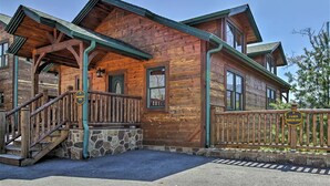 A rustic cabin-style building with a stone foundation, wooden exterior, and a porch with a green railing. - Stunning Views - Great Location (Gatlinburg)