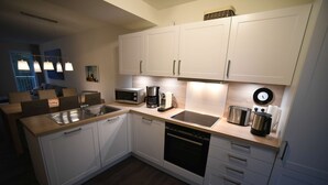 A modern kitchen with white cabinets, a microwave, a coffee maker, and a toaster. - Familienferienhaus Mare Frisium, Meerblick, am Deich, Waschtrockner, Sauna, Ofen (Wangerland)