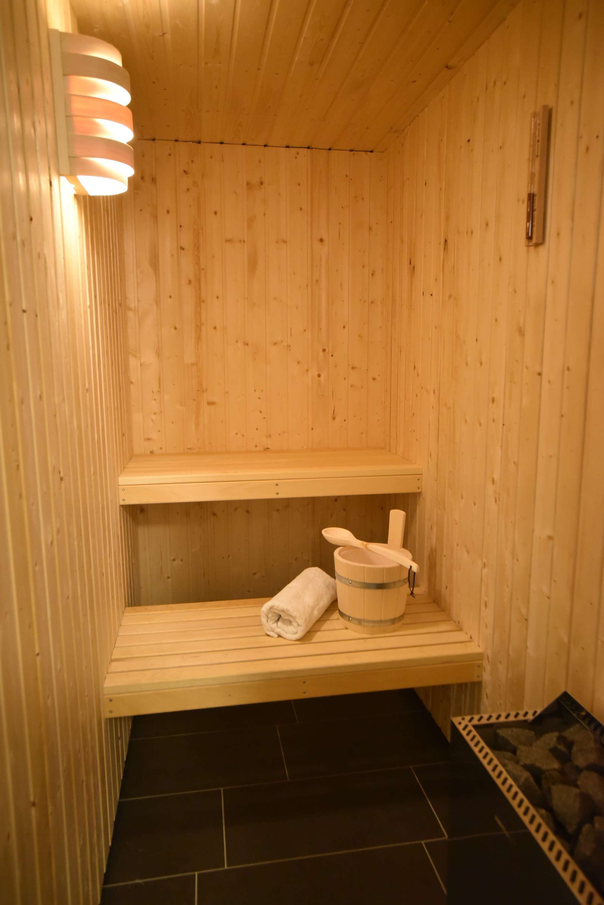 Una sauna de madera con un banco, una toalla y un cubo.