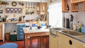 Une cuisine avec des meubles de rangement en bois, un évier et divers ustensiles de cuisine.