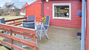Un bâtiment rouge doté d’une terrasse, de deux chaises et d’une table.