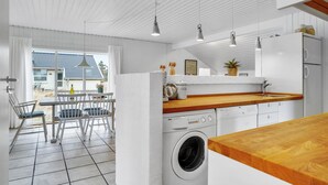 A modern kitchen with a wooden countertop, a washing machine, and a dining area with chairs and a table. - Lovely home in Thisted with WiFi (Thisted)