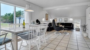 A spacious dining area with a white table and chairs, a black sofa, and a large window offering a view of the outdoors. - Lovely home in Thisted with WiFi (Thisted)