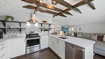 A modern kitchen with white cabinetry, stainless steel appliances, and a wooden ceiling.