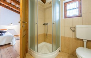 Une salle de bain avec une douche à parois de verre, des toilettes et un lit avec une serviette.