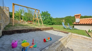 A children's play area with a swing set, a sandbox, and beach toys.