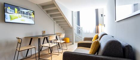 A modern interior with a staircase, a dining area, and a sofa.