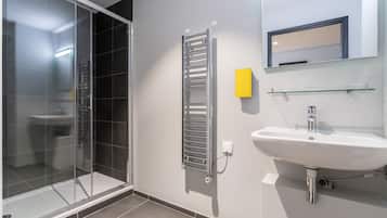 Un baño moderno con cabina de ducha de vidrio, toallero de pared, lavabo y espejo.