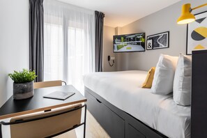 A modern hotel room with a bed, a desk, a chair, a potted plant, a TV on the wall, and a window with curtains. - Staycity Aparthotels, Bordeaux City Centre (Bordeaux)