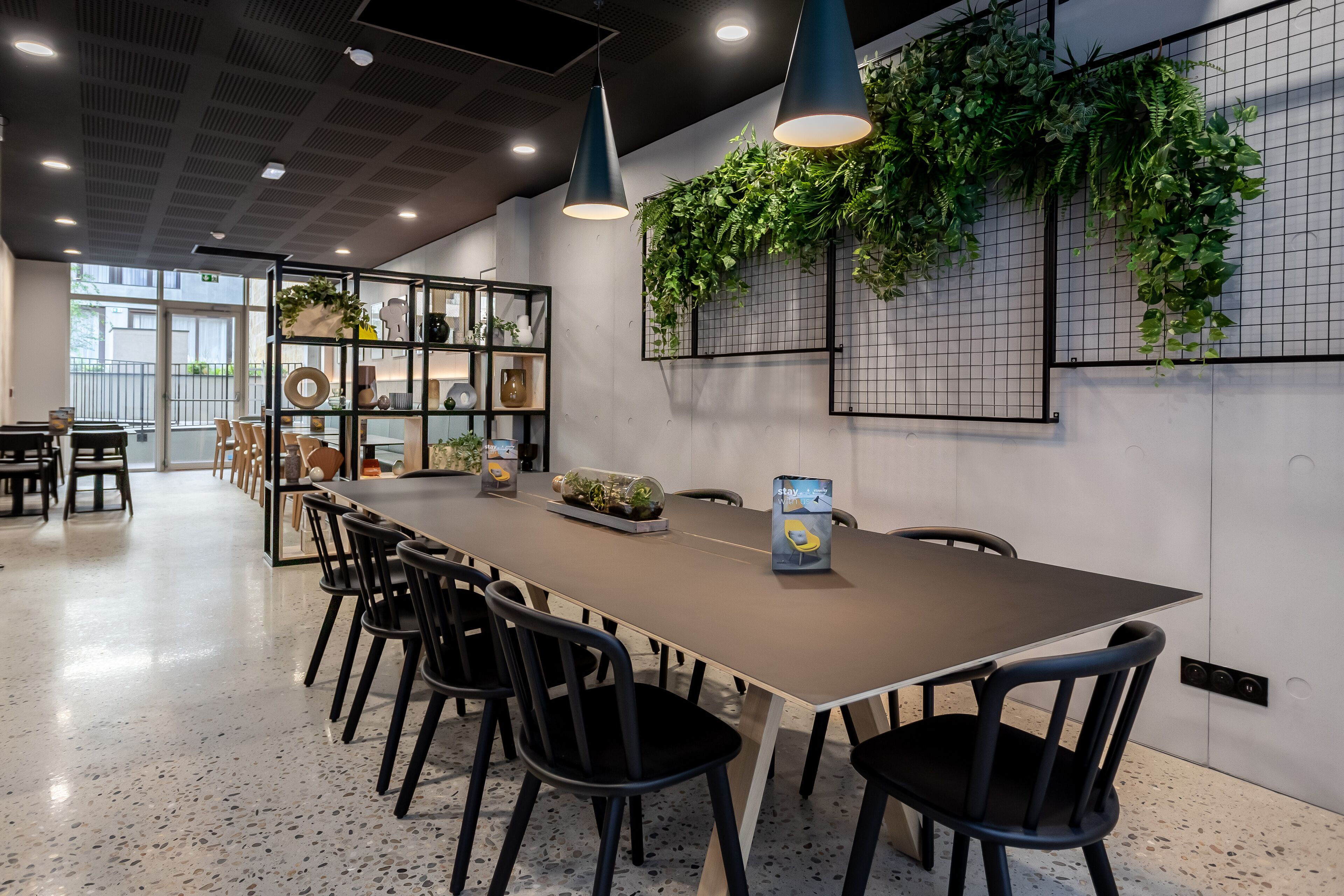 A modern conference room with a long table, black chairs, and pendant lighting.