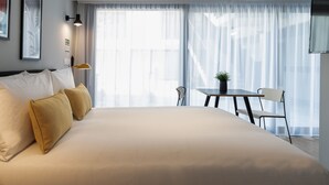A modern hotel room with a large bed, a small table, chairs, and a TV.
