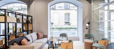 A modern living room with a sofa, chairs, a small table, and a bookshelf.