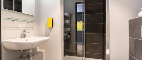 A modern bathroom with a glass shower enclosure, a white sink, and a toilet.