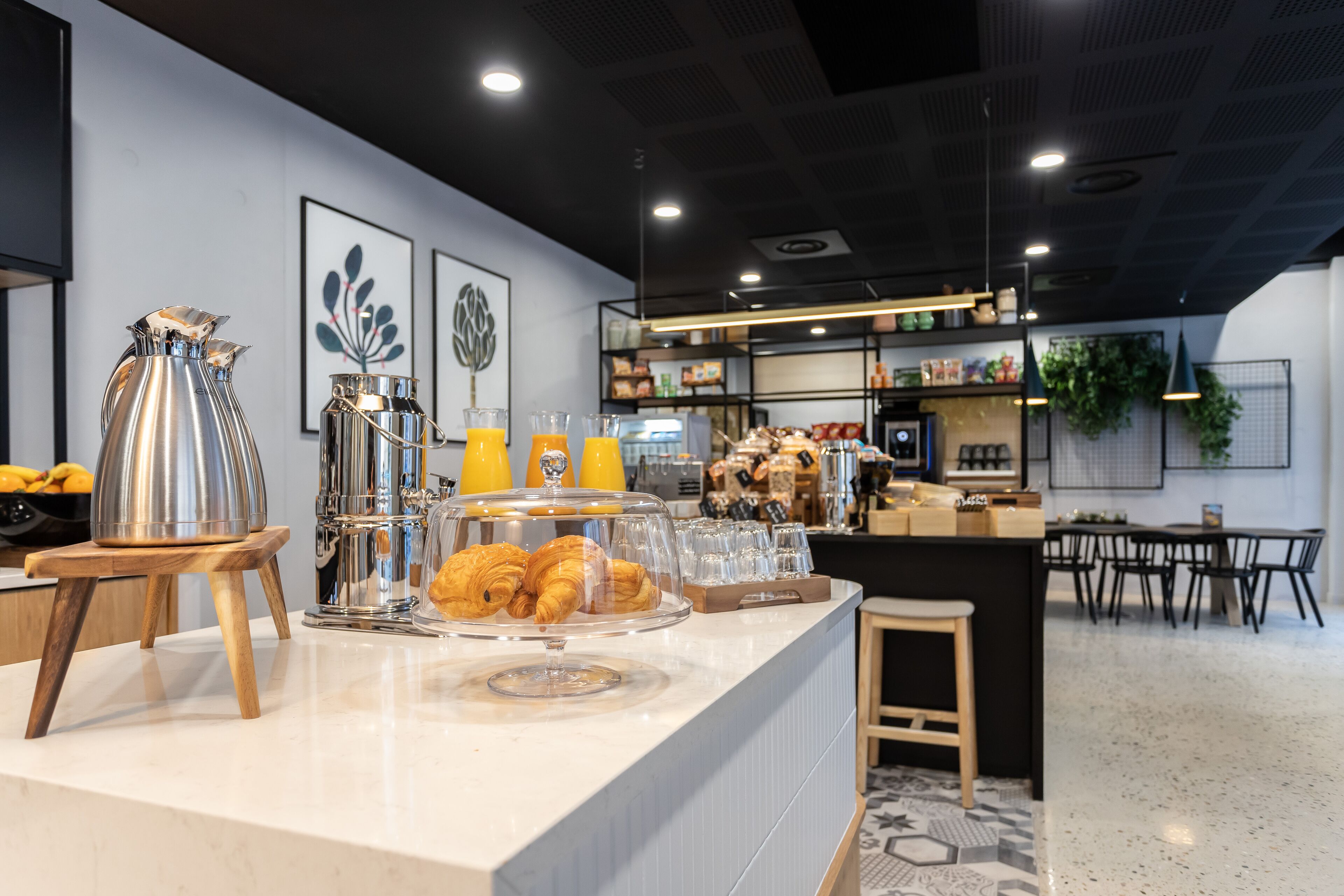 A breakfast bar with croissants, orange juice, and a coffee pot.
