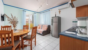 Una cucina compatta con frigorifero, macchina del caffè e zona pranzo con tavolo e sedie.
