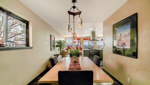 A dining area with a long table, chairs, a vase with flowers, and a hanging light fixture. - Relaxing, comfortable home for entertaining or enjoying the view (Rio Rancho)