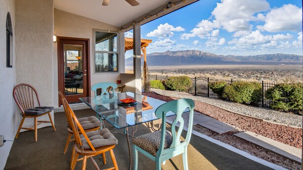A glass-top dining table with chairs, a ceiling fan, and a view of mountains. - Relaxing, comfortable home for entertaining or enjoying the view (Rio Rancho)