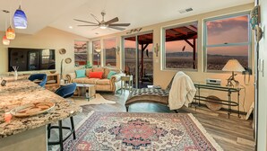 A spacious living area with a large window offering a view of the desert, a ceiling fan, and a dining area with a marble countertop. - Relaxing, comfortable home for entertaining or enjoying the view (Rio Rancho)