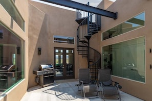 Une terrasse extérieure moderne avec un escalier en colimaçon, un barbecue et des sièges.