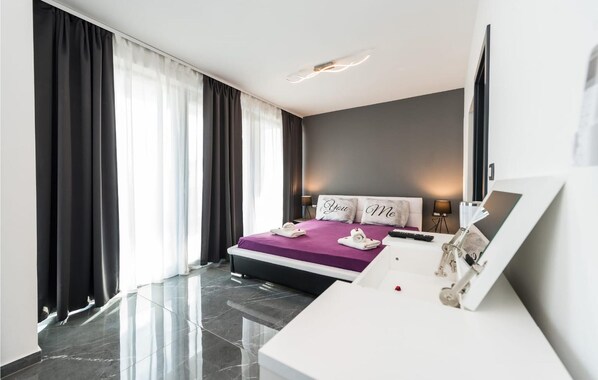 A modern hotel room with a large bed, a desk, and a view of the city.