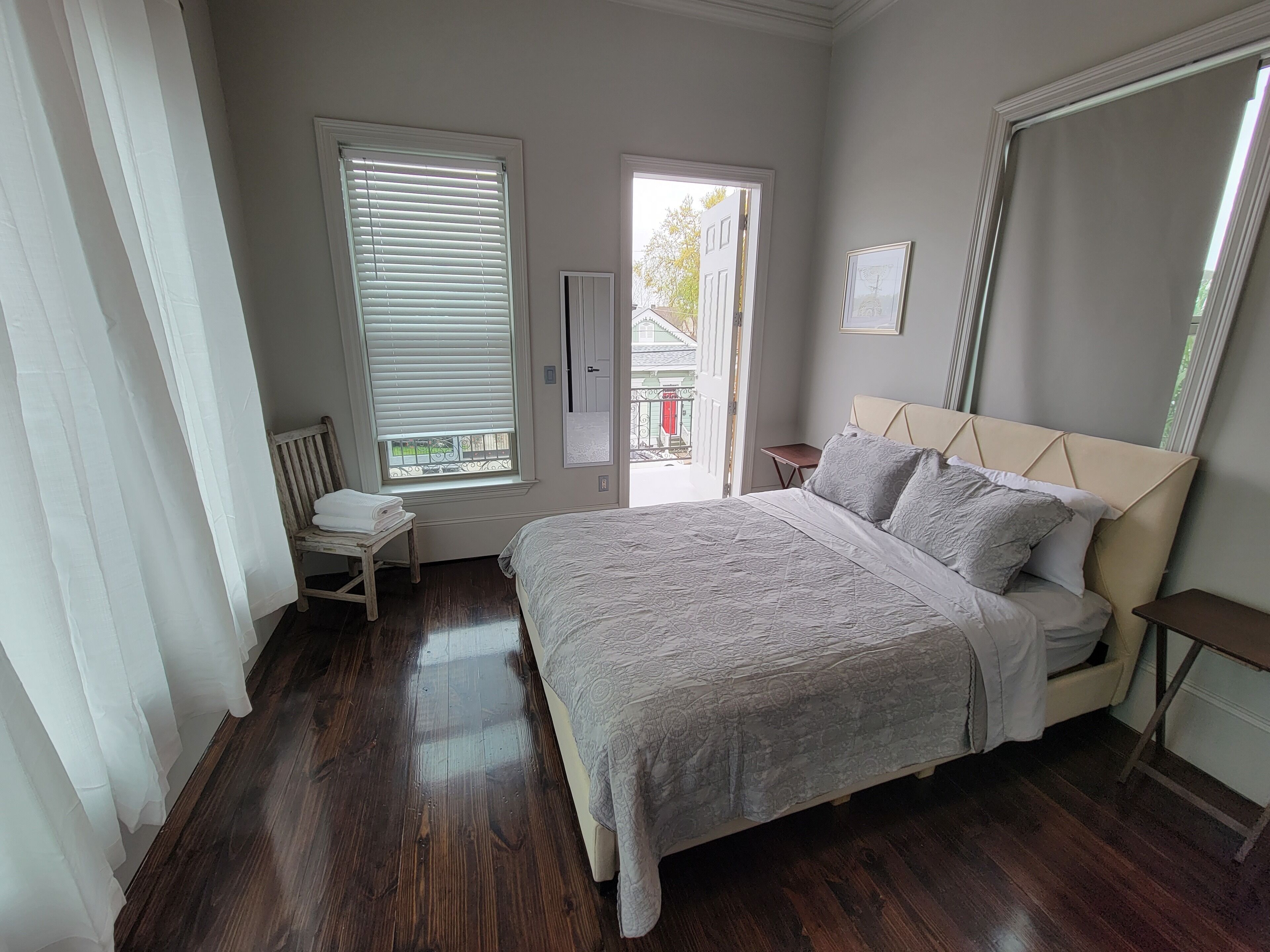 Une chambre à coucher avec un lit, une chaise, une petite table et une fenêtre avec des stores.