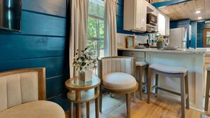 A room with a wooden ceiling, a kitchen area, and a seating area with two chairs and a small table. - Pops Lookout Mountain Luxury Tiny Cabin with Spa (Chattanooga)