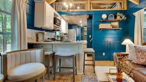 A cozy interior with a kitchen, bar stools, a sofa, and a decorative vase. - Pops Lookout Mountain Luxury Tiny Cabin with Spa (Chattanooga)