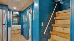 A room with a bed, a wooden staircase, and a blue wall. - Pops Lookout Mountain Luxury Tiny Cabin with Spa (Chattanooga)