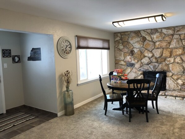 A dining area with a stone wall, a clock, and a window with blinds. - Mystic Manor Monroe 4 Bed Farm House- 10 min walk to Hot springs (Monroe)