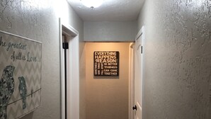 A hallway with a motivational quote on the wall and a door leading to another room.