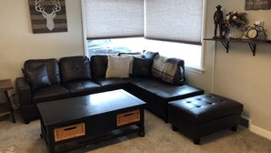 A corner living room with a sectional sofa, a coffee table, and a side table.