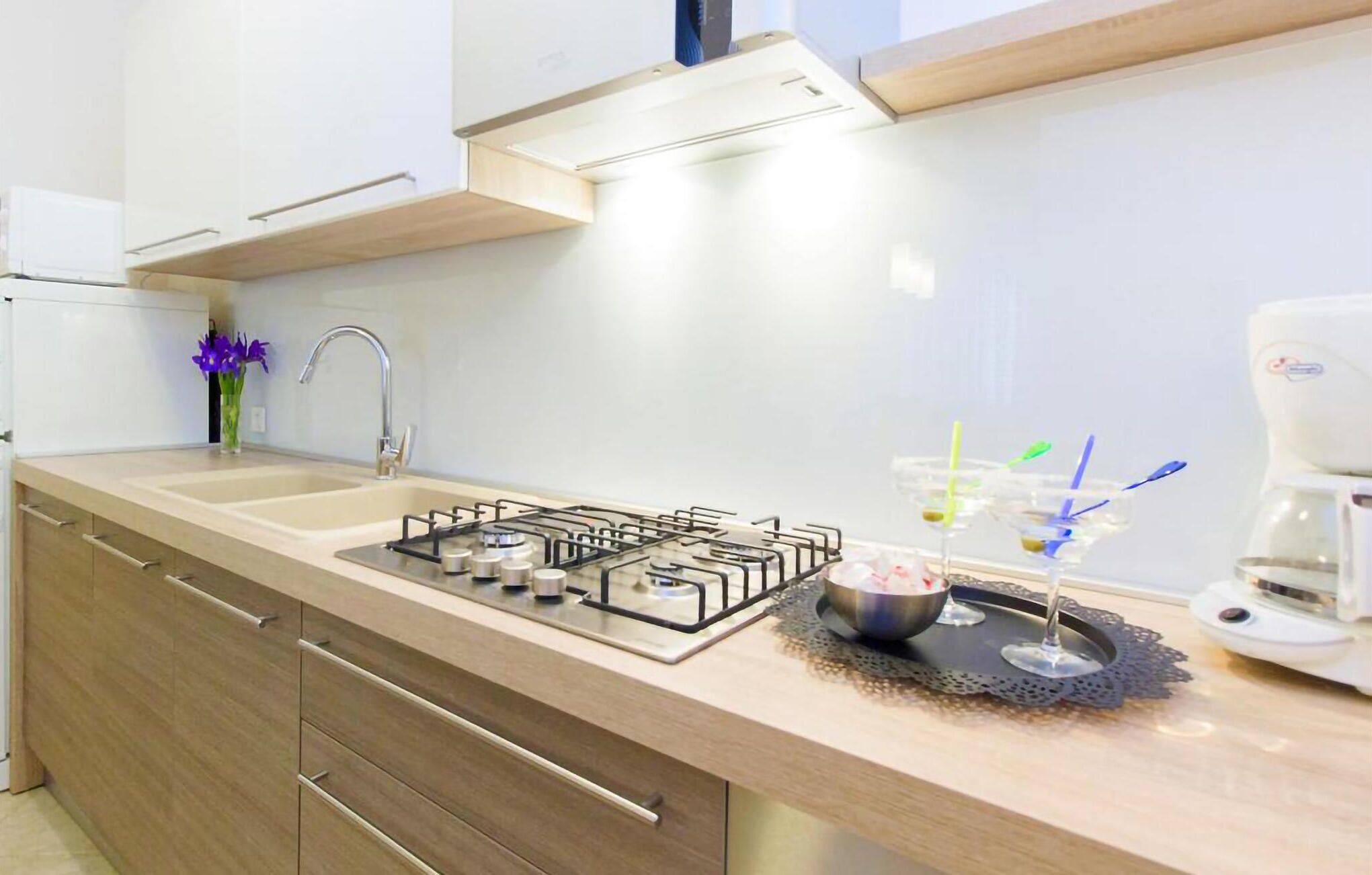 Een moderne keuken met een gasfornuis, spoelbak en koffiezetapparaat.