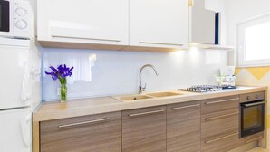A modern kitchen with white cabinets, a stainless steel sink, a gas stove, and a built-in oven.
