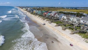 Una zona costera con casas frente al mar, una playa arenosa y el océano.