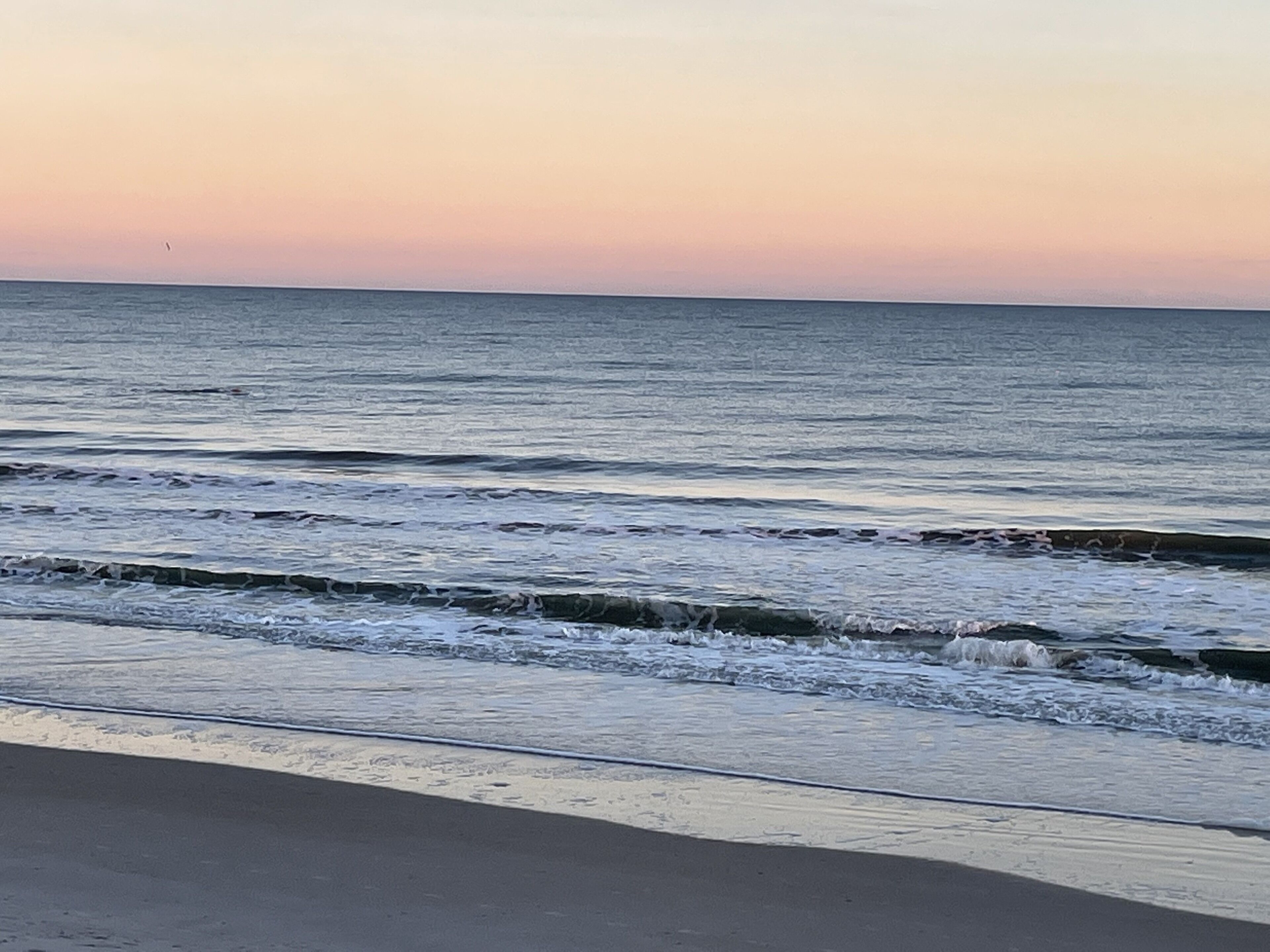 A beach with waves and a clear sky.