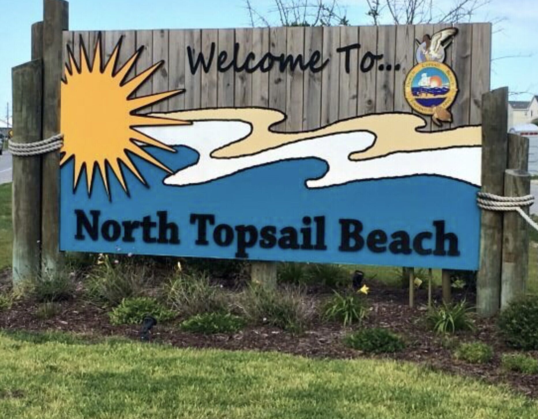 A welcome sign for North Topsail Beach with a sun and waves graphic.