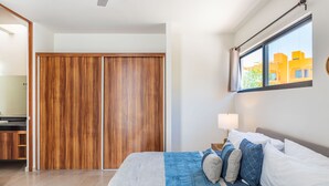 A bedroom with a bed, a nightstand, a window with a view, and a wooden wardrobe. - Retreat into Exotic Paradise in Riviera Maya, 15 minute walk to beach (residencial El Cielo, Solaridad)