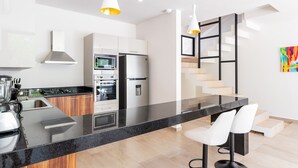 A modern kitchen with a central island, stainless steel appliances, and a staircase with a minimalist design. - Retreat into Exotic Paradise in Riviera Maya, 15 minute walk to beach (residencial El Cielo, Solaridad)