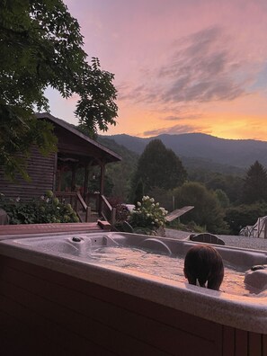 Ein Whirlpool mit Blick auf Berge und eine Holzhütte.