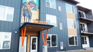 A modern building with a large mural of a cowboy and horse, a covered entrance, and the number 2222C. - Brand new 2021 3 bedroom 2 bath condo. Great location just off interstate 90. (Livingston)