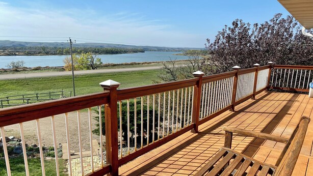 A wooden deck with a view of a lake and distant hills. - Farm Island Missouri River Views (Pierre)