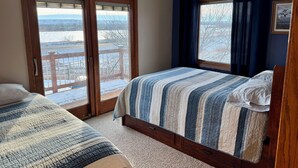 A bedroom with a bed, a window with curtains, a ceiling fan, and a view of a snowy landscape. - Farm Island Missouri River Views (Pierre)