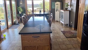 A kitchen with a large island, a dining table, and chairs. There is a view of a lake through the windows. - Farm Island Missouri River Views (Pierre)