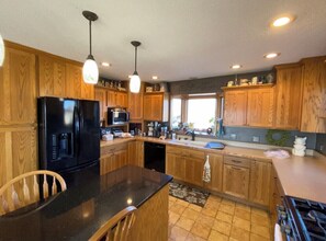Enjoy cooking in this well-equipped kitchen with a central island, refrigerator, microwave, and stove.