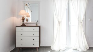 Une salle de bain avec un meuble-lavabo blanc, un miroir et une fenêtre agrémentée de rideaux blancs.