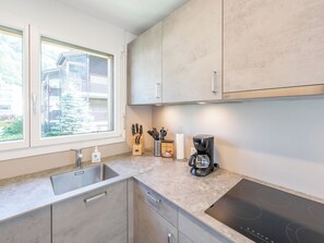 A modern kitchen with a built-in stove, a coffee maker, and a window with a view of a residential area.