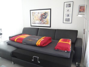 A modern living room with a grey sofa, a small table, and a framed artwork on the wall.