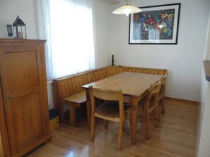 A dining area with a wooden table and benches, a cabinet, and a painting on the wall.