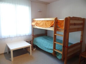 Un lit superposé avec une échelle, une petite table et une fenêtre avec des rideaux.